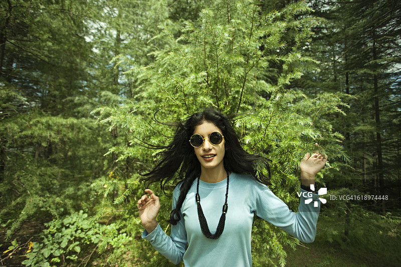 酷酷的女孩戴着墨镜站在大自然中。图片素材