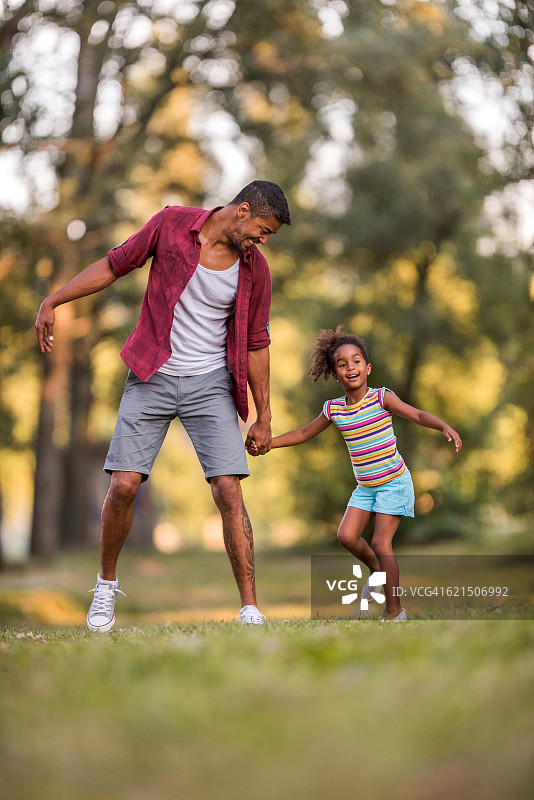 快乐的爸爸和女儿在公园玩得开心。图片素材