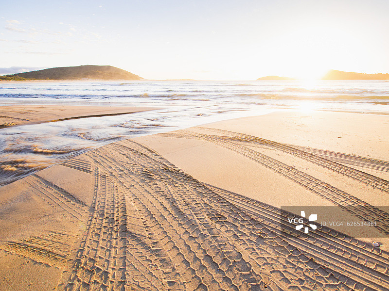 澳大利亚，新南威尔士州，杰维斯湾，日落时海滩上的轮胎痕迹图片素材