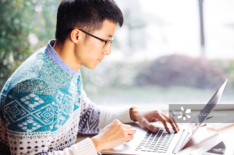 年轻的亚洲男子学生使用笔记本电脑图片素材