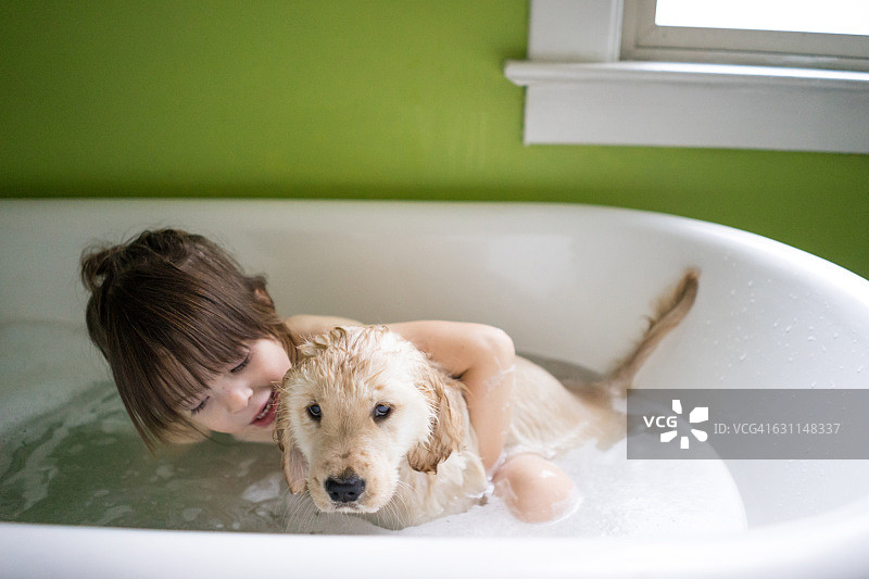 女孩和金毛小狗坐在浴缸里图片素材