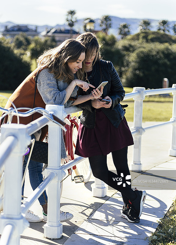 两个年轻的女人在户外看手机图片素材
