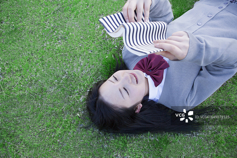 在草坪上看书的日本高中生图片素材
