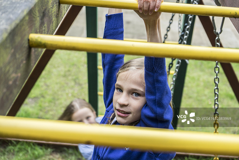 一个穿着校服的十岁女孩在操场上爬器械图片素材