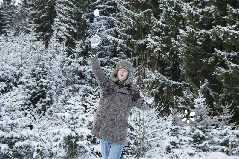 德国巴伐利亚，一个年轻人在冬天扔雪球图片素材