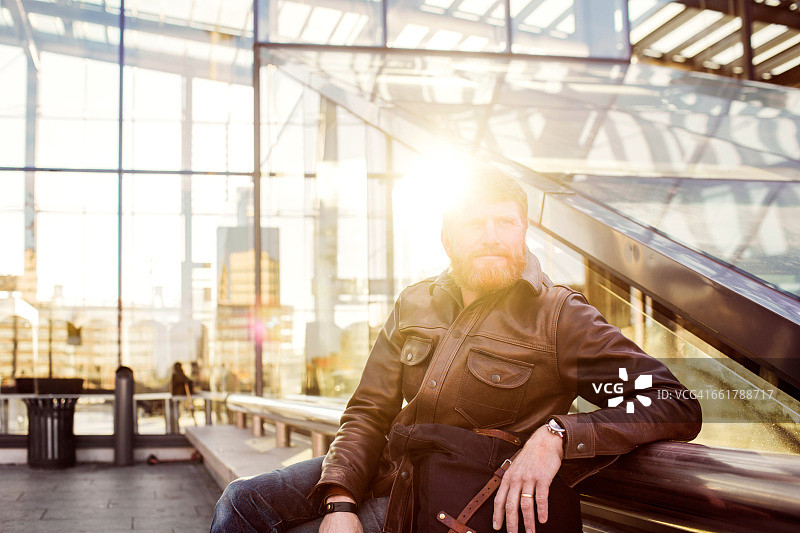 阳光明媚的日子里，一位深思熟虑的商人坐在中央车站外图片素材