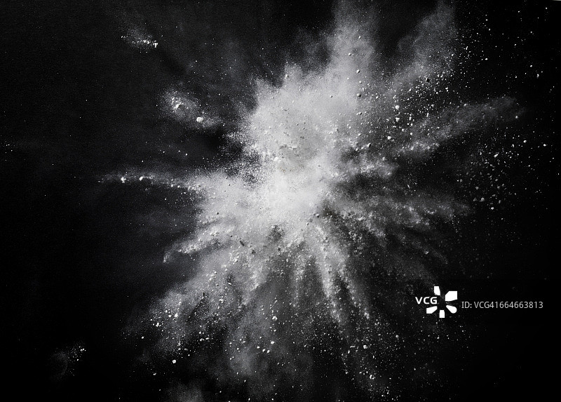 白色的灰尘在空中爆炸，背景是黑色的图片素材
