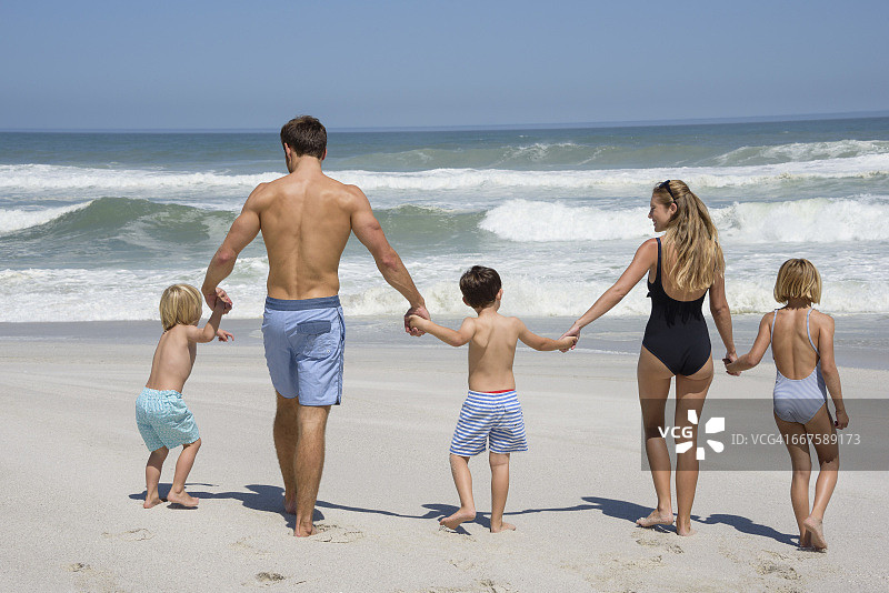 一个家庭在海滩上散步的后视图图片素材