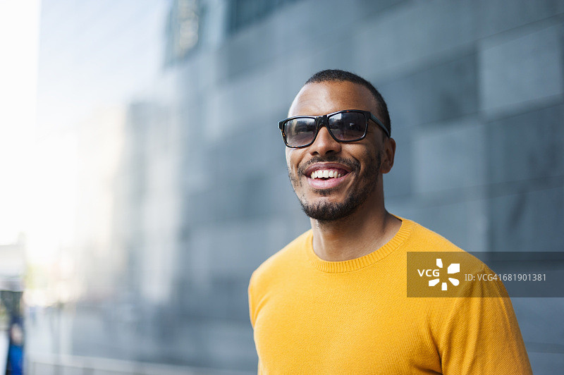 一幅微笑的男人的肖像，穿着黄色套衫，戴着太阳镜图片素材