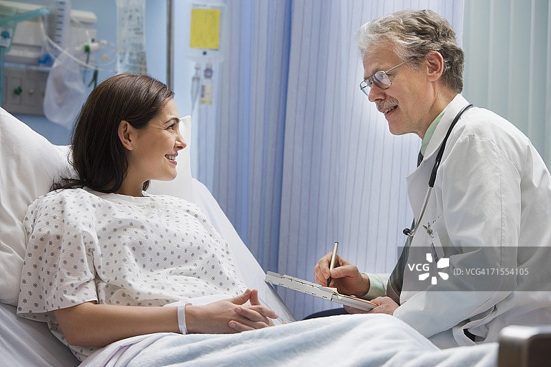 男医生在病床上与女病人交谈图片素材