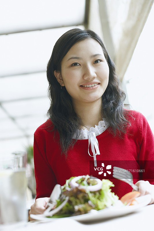一个年轻女人的肖像坐在桌子在一个餐馆微笑图片素材