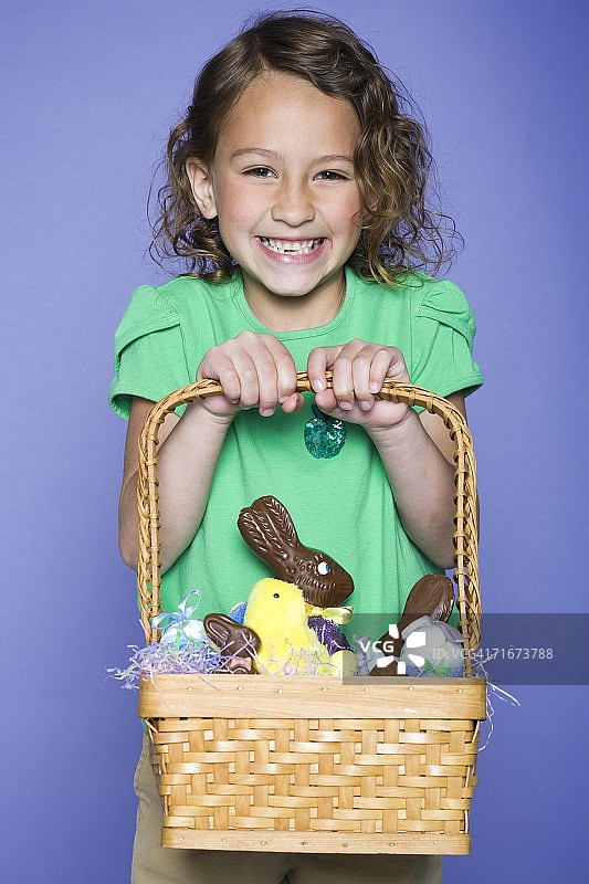 一个女孩在柳条篮子里抱着复活节兔子和复活节彩蛋的肖像图片素材