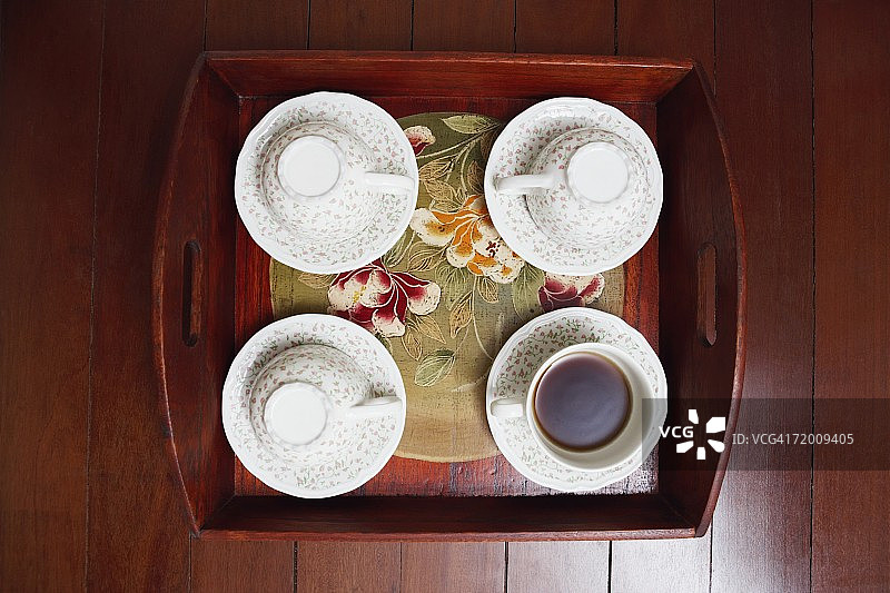 高角度的茶杯与托盘在硬木地板上图片素材