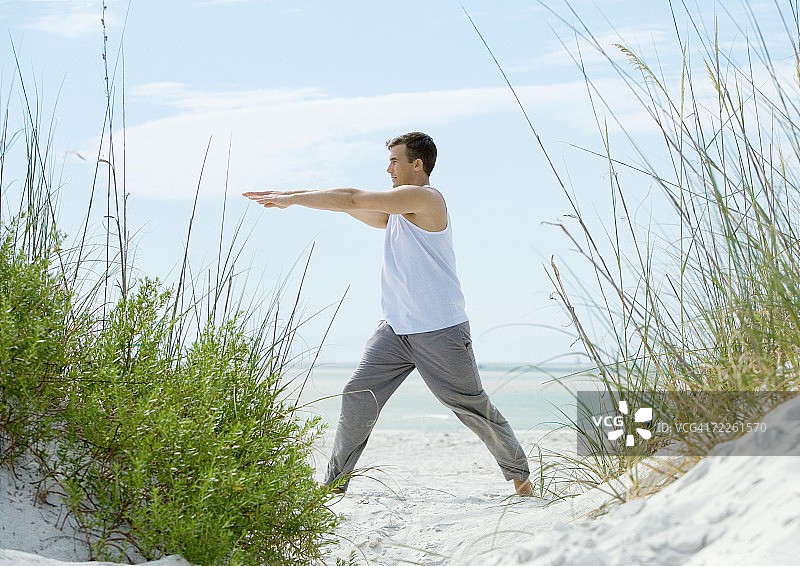 在海滩上做伸展运动的男人图片素材