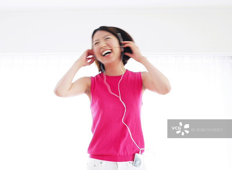 亚洲妇女听音乐和微笑图片素材