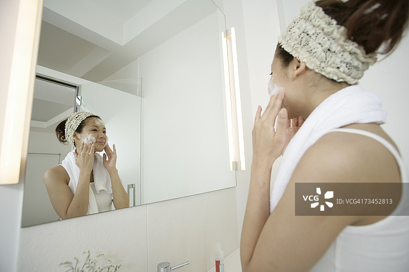 一个年轻女子在脸上涂肥皂的侧面照片图片素材