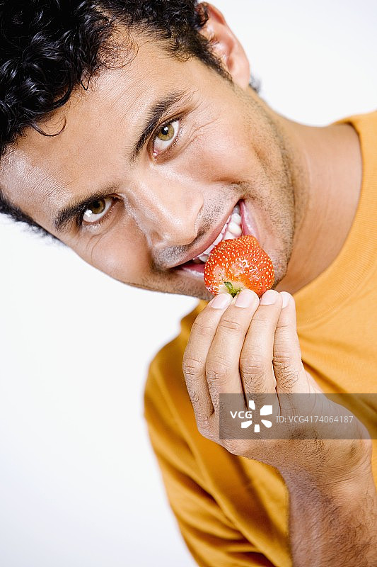 一个年轻人吃草莓的肖像图片素材