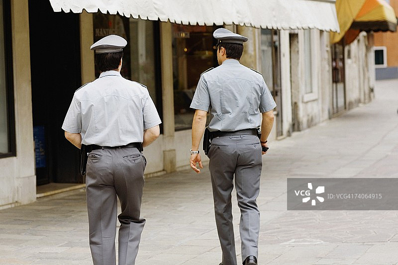 两名警察走向一座建筑的后视图，威尼斯，威尼托，意大利图片素材