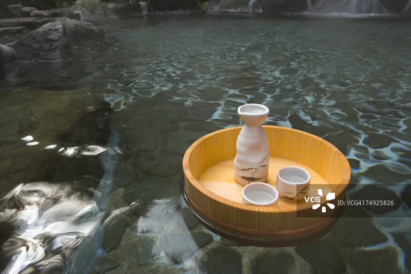 清酒酒瓶和杯子漂浮在一个日本公共浴池上，温泉，高角度观赏，日本图片素材