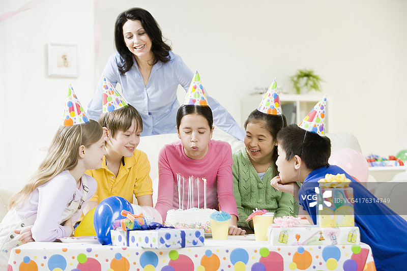 妇女和儿童(8-11岁)，在生日蛋糕上吹蜡烛图片素材