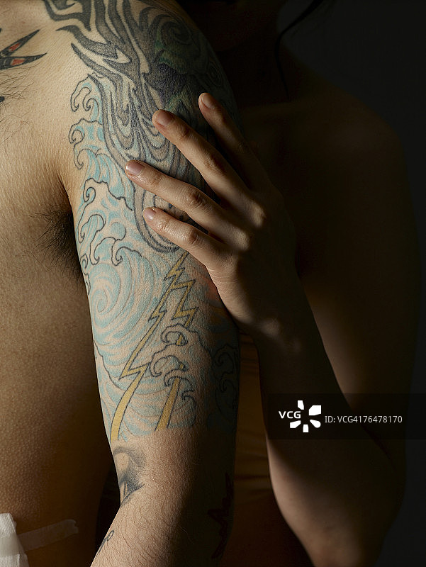 女人的手放在纹身男人的手臂上图片素材