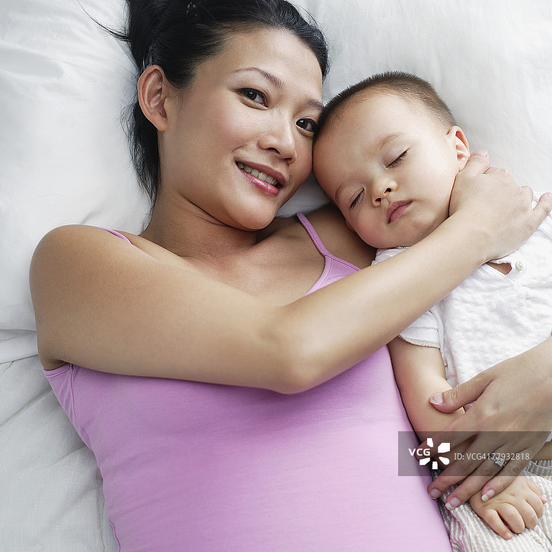 婴儿躺在床上的女人图片素材