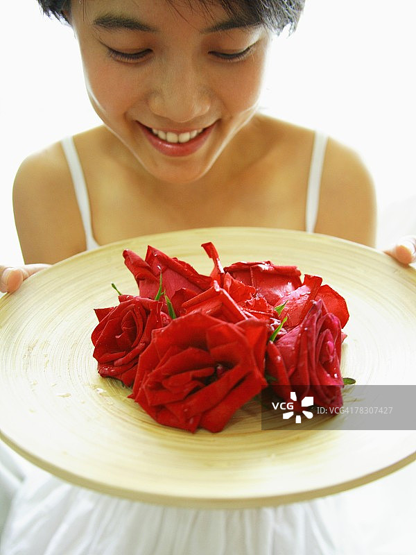 一个年轻女子拿着一盘玫瑰的特写图片素材