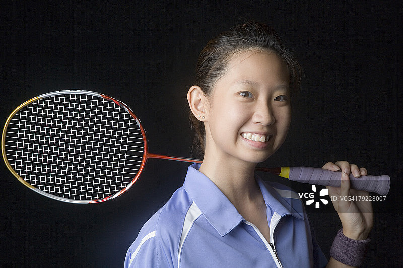一个年轻女子的肖像拿着羽毛球拍和微笑图片素材