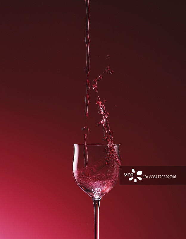 酒杯倒酒，正面，红色背景图片素材