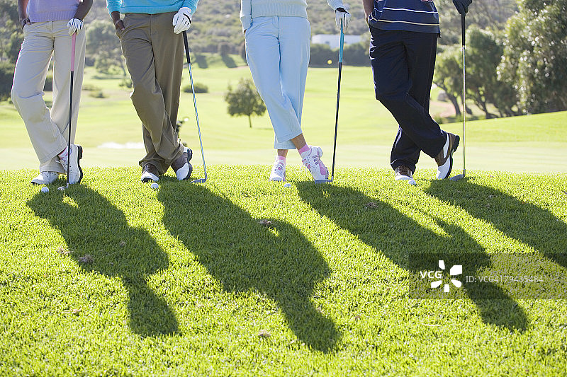 四个高尔夫球手站在一边，腰下图片素材