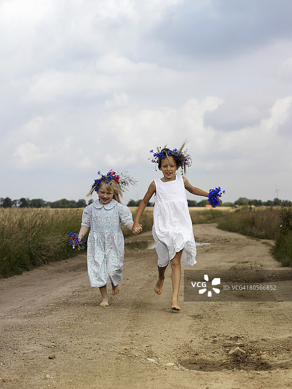 两个年轻女孩在乡间小路上奔跑图片素材
