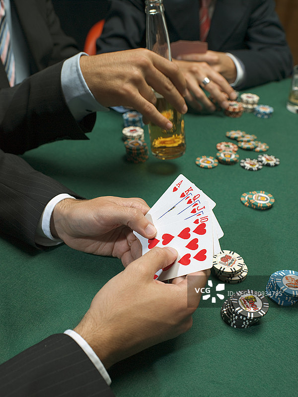 男子在扑克游戏中持有扑克牌的细节图片素材