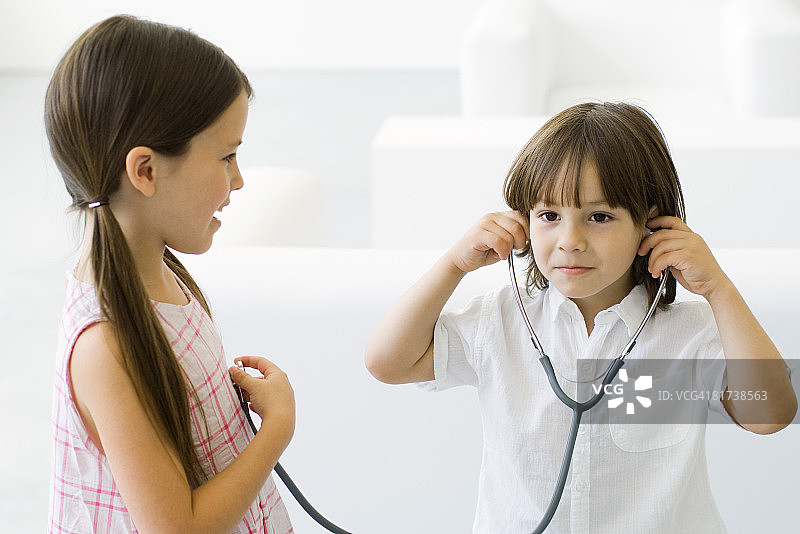小男孩用听诊器听女孩的心跳图片素材