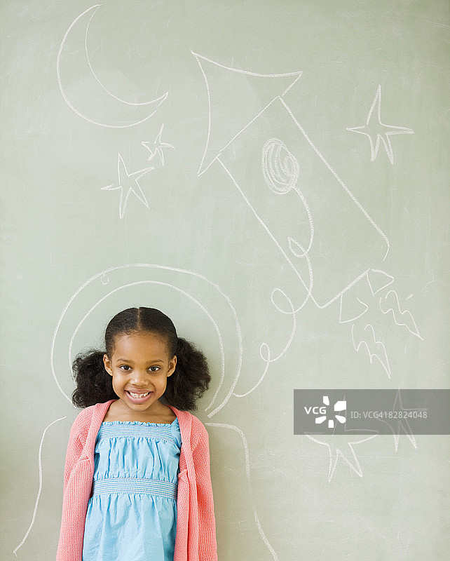 混血女孩站在黑板上的图画旁边图片素材