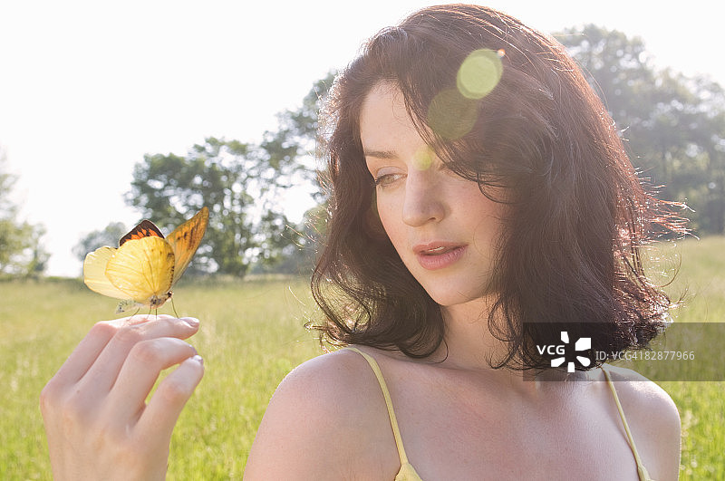 年轻女子看着手上的蝴蝶图片素材
