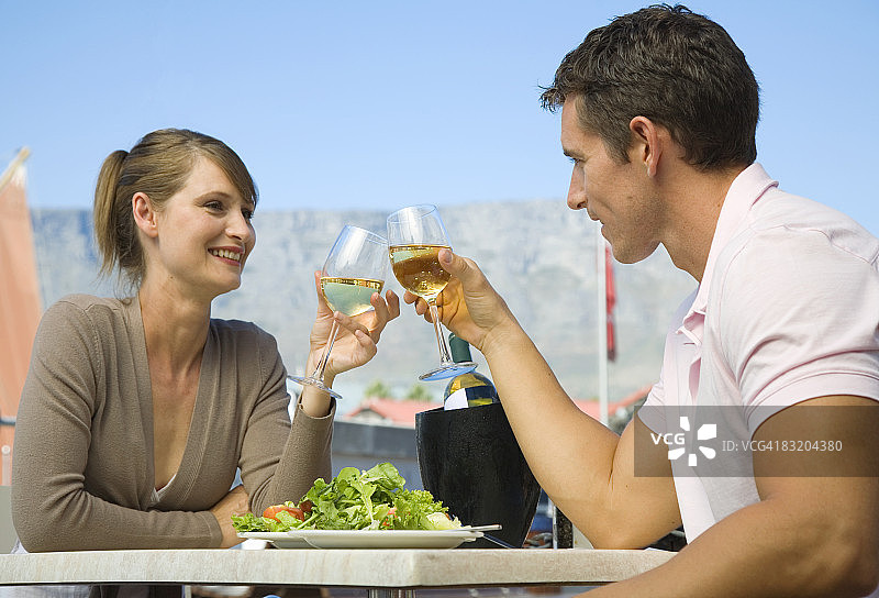 南非西开普省开普敦，一对夫妇在海滨用餐，餐桌山为背景图片素材