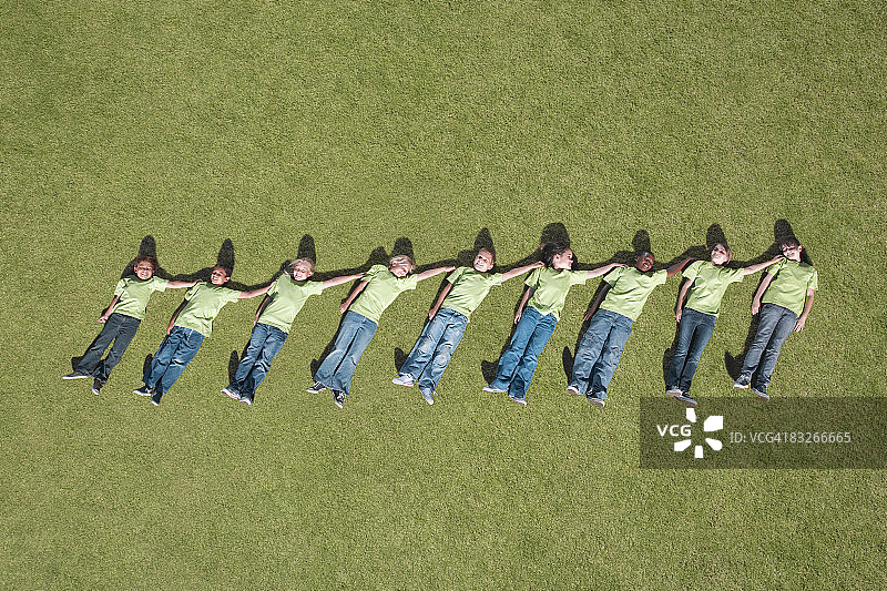 一群孩子躺在草地上，按高度上升的顺序排列图片素材
