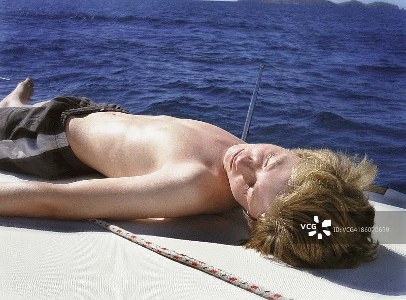 十来岁的男孩在甲板上晒太阳图片素材