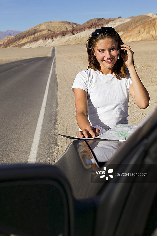 沙漠路上的女人带着地图和手机图片素材