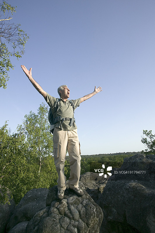 快乐的人站在树林里的岩石上图片素材
