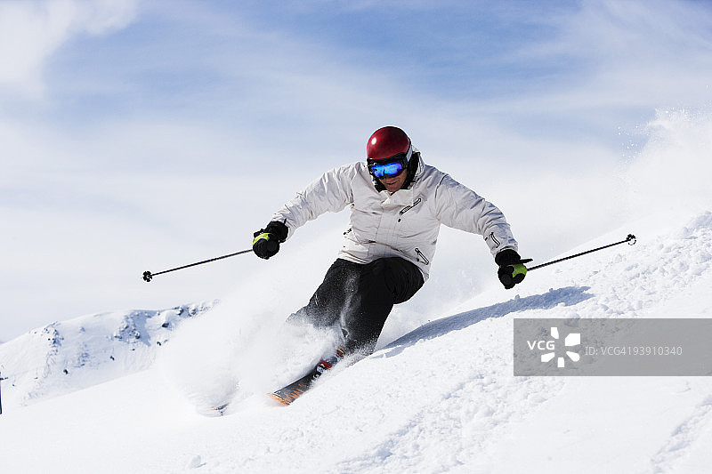 戴着红色头盔的白衣男子在滑雪道外。图片素材