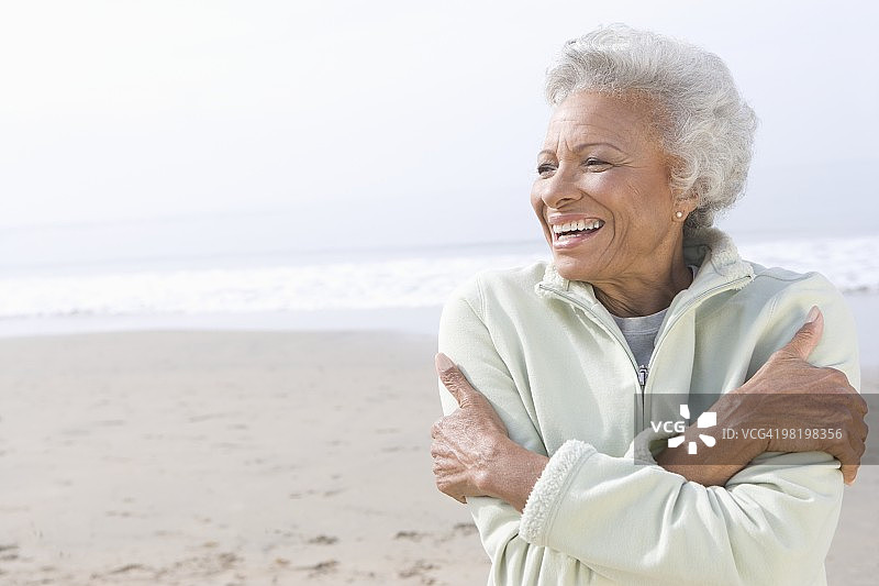 老妇人站在沙滩上取暖图片素材