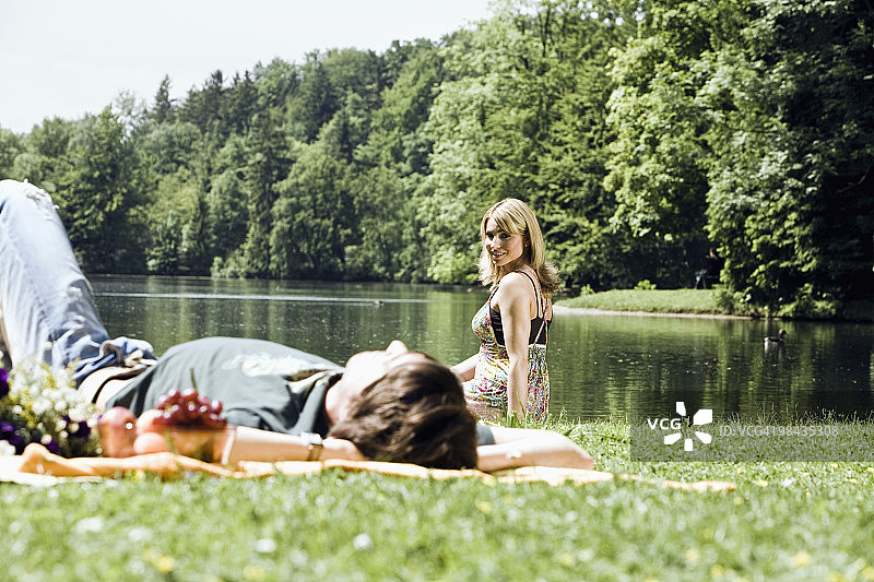年轻女子看着男友睡在草地上图片素材