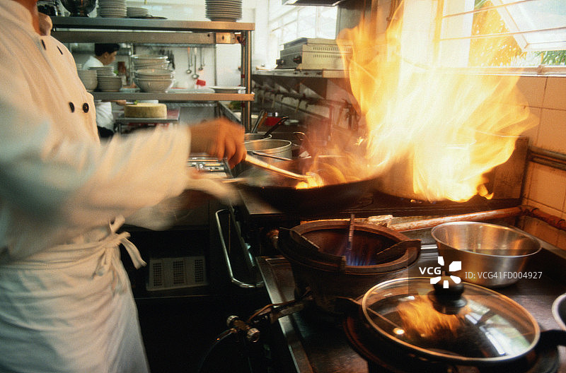厨师在商业厨房烹饪，中间部分，侧视图图片素材