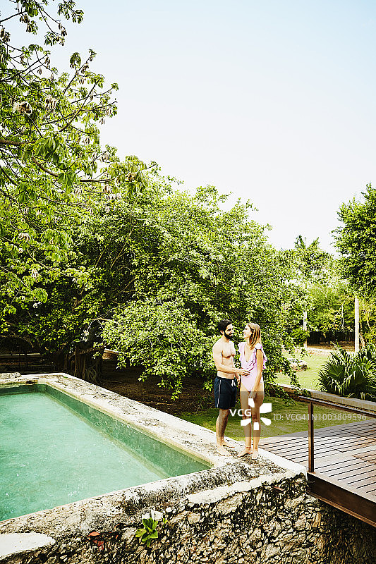 一对大笑的夫妇站在豪华热带度假村的跳水池边图片素材
