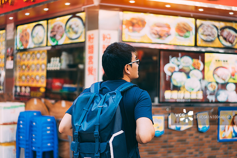 一个年轻的旅行者正在香港旺角寻找一些吃面条的餐馆。图片素材