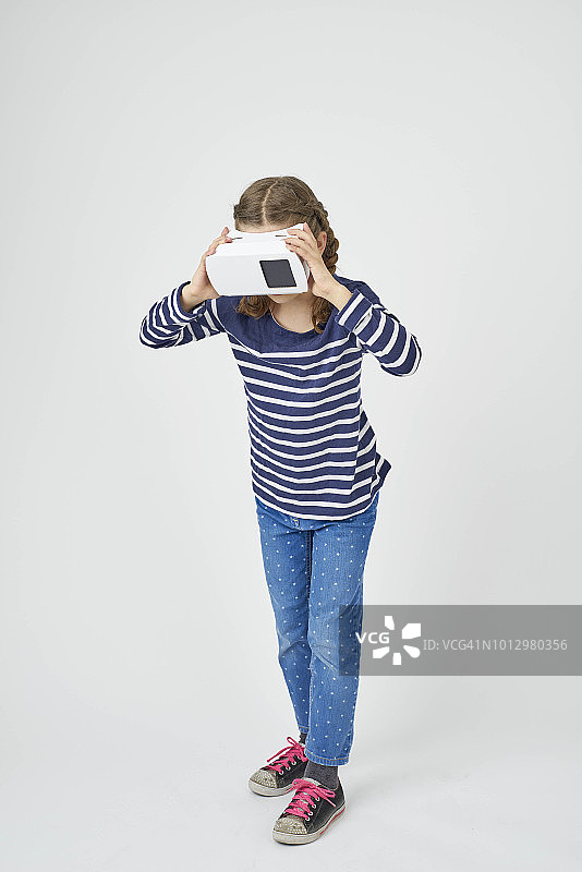 一个孩子拿着虚拟现实的观看器站在面前图片素材