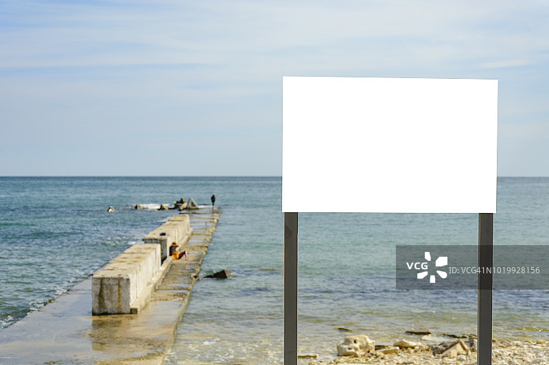 海滩上的空白标志对着海水和码头。图片素材