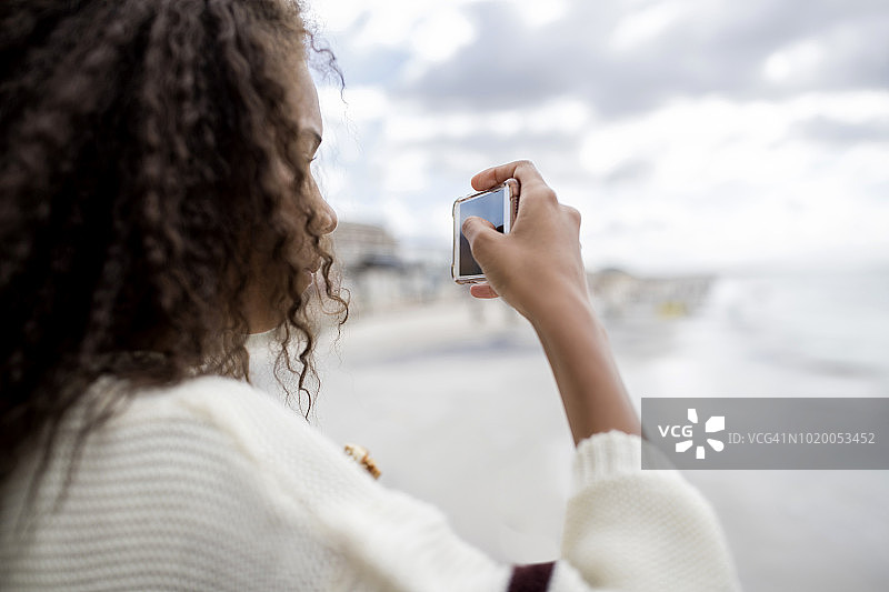 一个年轻女子在海滩上拿着手机图片素材