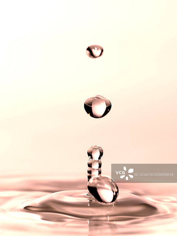 一组水滴悬在空中，落在水面上，形成图形和抽象的形式，在浅粉色的背景。图片素材
